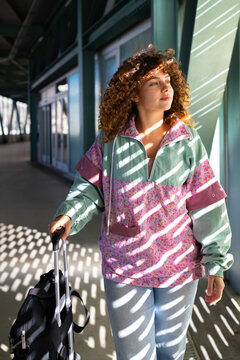 White woman with suitcase standing in sunlit corridor in Spain