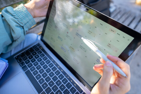 White person using digital calendar on tablet laptop outdoors