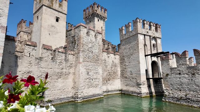 Scaliger Castle in Sirmione viewed from the entrance bridge, showing its medieval stone walls, fortified towers and surrounding moat