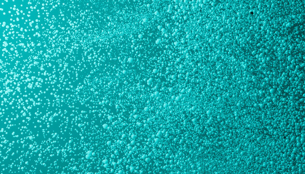 Turquoise liquid surface covered with small bubbles creating foam