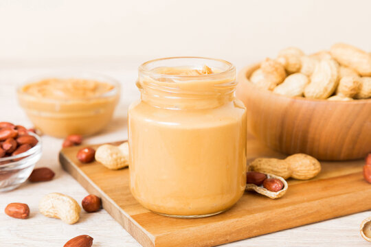 Bowl of peanut butter and peanuts on table background. top view with copy space. Creamy peanut pasta in small bowl