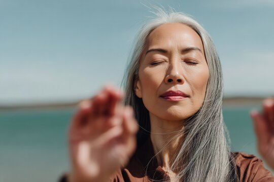 Serene woman with closed eyes practicing mindfulness outdoors by the ocean