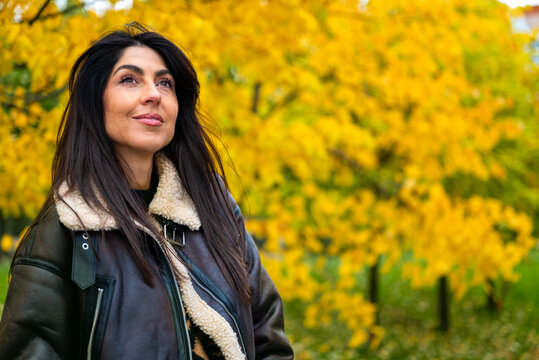 Beautiful young woman with leather jacket smiling  in the autumn park 