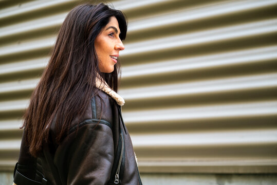 Beautiful young brunette woman with brown leather jacket and hat outdoor