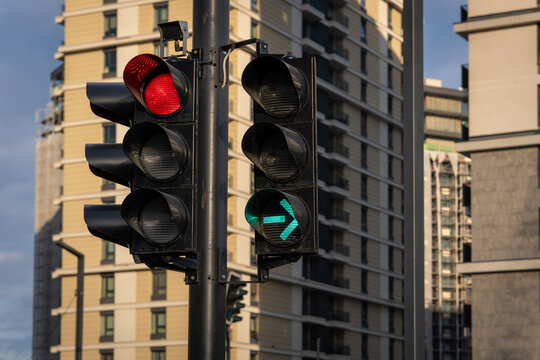 Urban traffic signal showing a green right turn arrow while another light displays red, with modern buildings in the background.