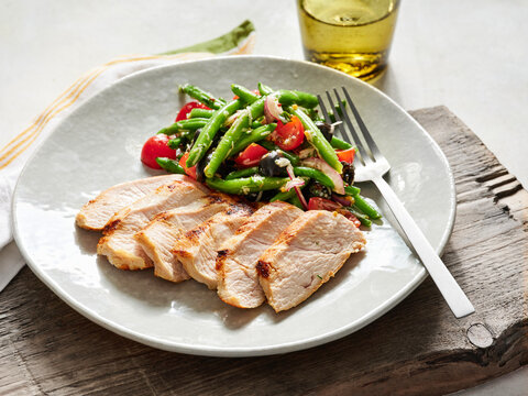 Grilled chicken breast with vibrant green beans and tomato salad, healthy dining option for restaurants