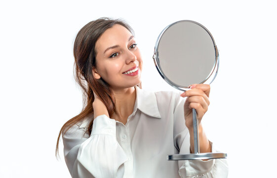 Beautiful woman looking in the mirror, touching her face with her hand. Dermatology. Woman face examining skin with mirror concentrated closeup