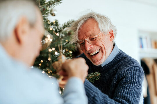 Two Laughing Senior Men Celebrating Together by Christmas Tree at Home