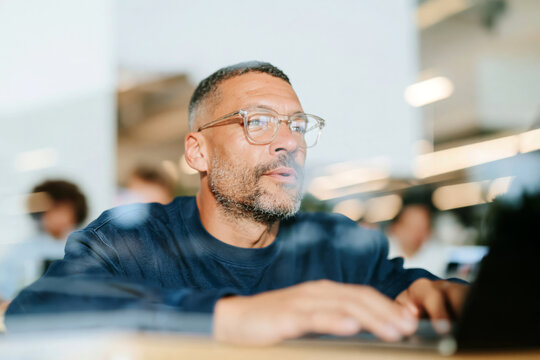 Confident Mature Man with Glasses and Beard Sitting in Bright Modern Office