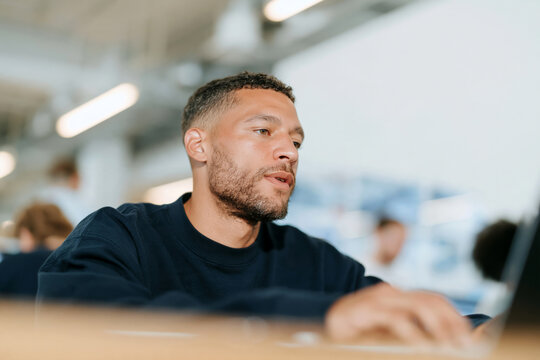 Confident Mature Man with Glasses and Beard Sitting in Bright Modern Office