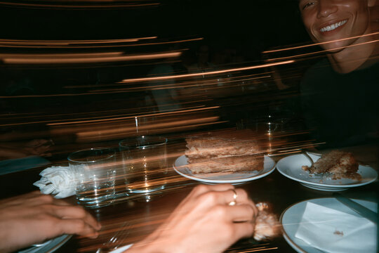 Motion Blur of Friends Sharing Dessert at Restaurant Table in Nightlife Setting
