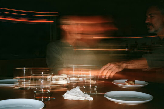 Motion Blur of Friends Sharing Dessert at Restaurant Table in Nightlife Setting