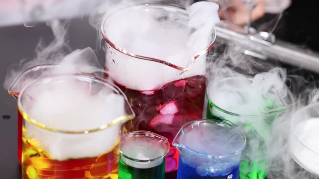 Colorful liquids bubble and smoke in beakers science experiment with dry ice or chemical reaction.