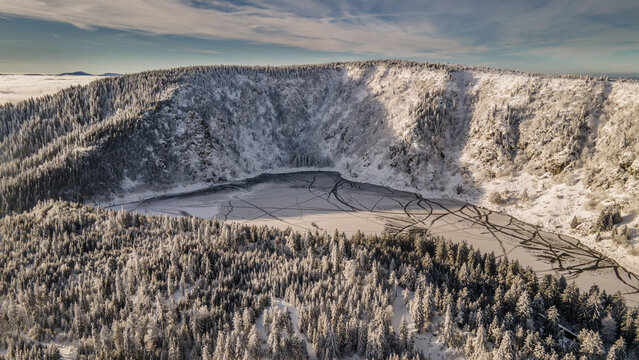 FRANCE. ALSACE. HAUT-RHIN 68 AERIAL VIEW OF LAC BLANC, A HIGH-ALTITUDE LAKE AT 1,055 M NESTLED IN A GLACIAL CIRQUE IN THE VOSGES MOUNTAINS AND SURROUNDED BY TREES, COVERED IN SNOW IN WINTER.