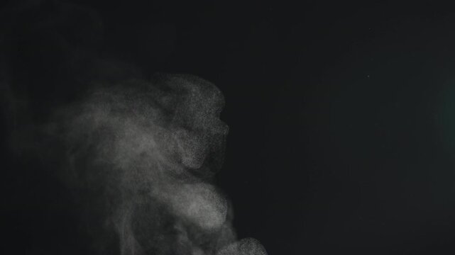 Slow motion steam rising from boiling water over black background