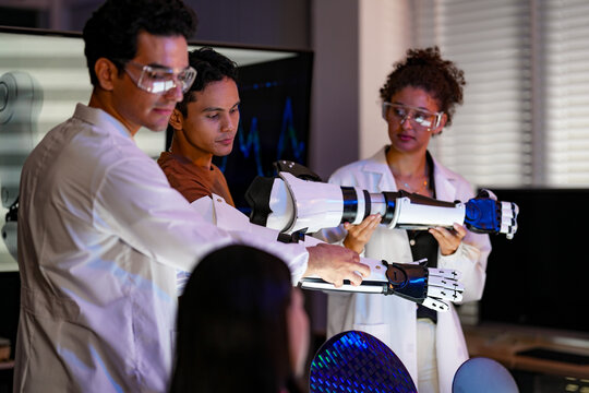 An engineer explains the change she has just made as the readings shift on the monitor behind inside a dimly lit research and development laboratory late in the working day