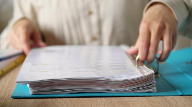 Close Up of Hands Holding Thick Blue Ring Binder with Documents, Office Paperwork and Archiving Concept