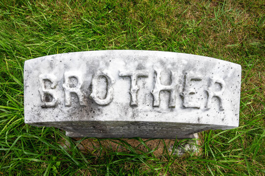 High angle closeup view of ancient gravestone that reads BROTHER green grass background with copy space