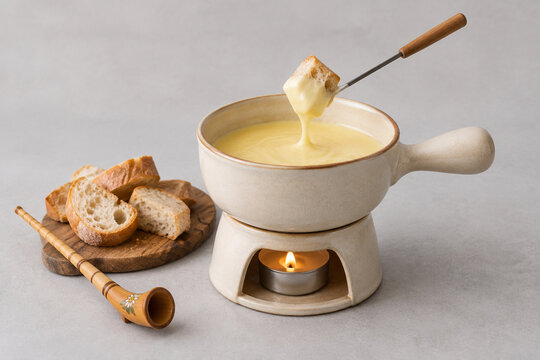 Ceramic cheese fondue pot with melted cheese, bread and carved alphorn, cozy dining concept