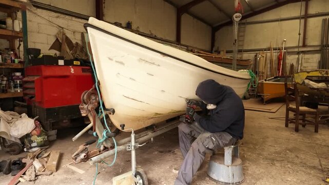 Man repairing gelcoat damage on fiberglass fishing boat