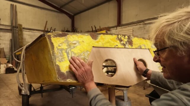 Wooden boat builder repairing transom of sailboat