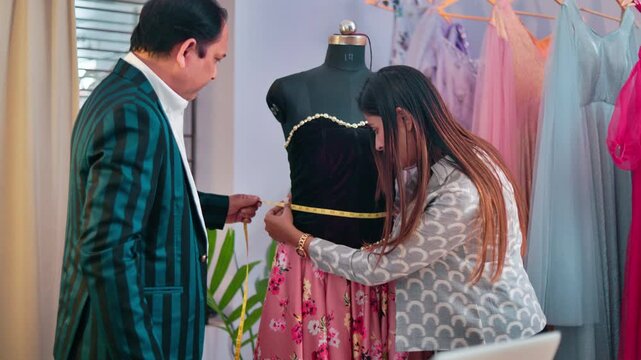 Fashion professionals examining the fit and waist measurement of a garment displayed on a dummy during garment design work.