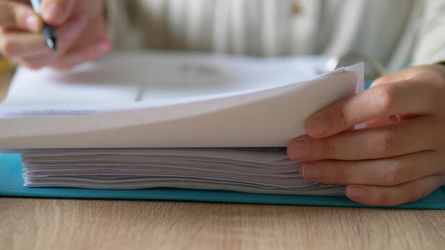 Close Up of Hands Turning Pages in Thick Document Folder and Writing with Pen, Financial Audit and Paperwork Concept