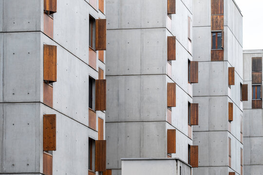 Raw concrete apartment facades in La Confluence, Lyon, France, with wood window shutters creating a minimalist pattern in modern residential architecture