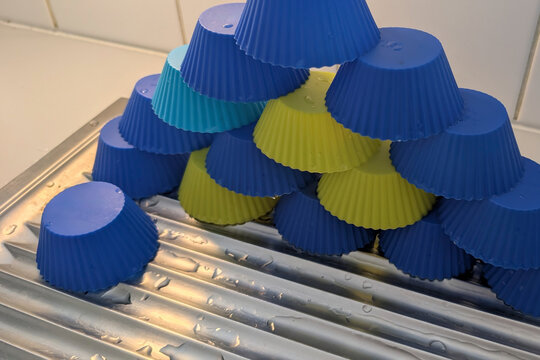 Colorful silicone baking cups stacked in a pyramid shape on a drying rack in a kitchen environment