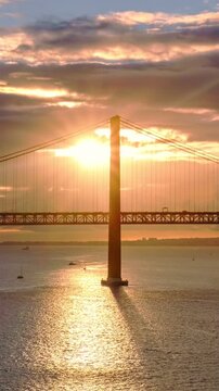 Time-lapse of 25 de Abril Bridge famous tourist landmark of Lisbon connecting Lisboa and Almada on Setubal Peninsula over Tagus river on sunset. Lisbon, Portugal.
