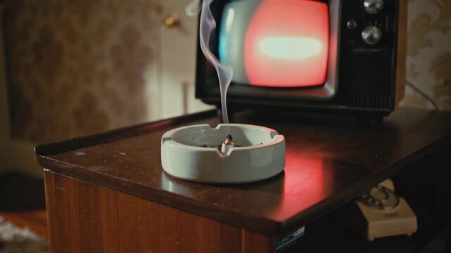Ember glowing, cigarette in white ceramic ashtray releasing smoke on retro side table