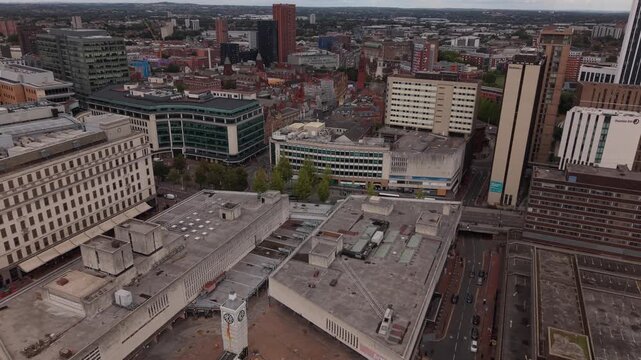 Aerial drone view of Birmingham city centre revealing contrasting architectural styles, from large office blocks and urban roads to dense historic brick buildings and modern developments.