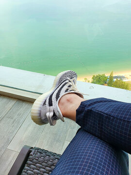 Person wearing Adidas Yeezy Boost 350 V2 Zebra sneakers relaxing on hotel balcony overlooking ocean view on March 15, 2020 in Pattya, Chonburi, Thailanf