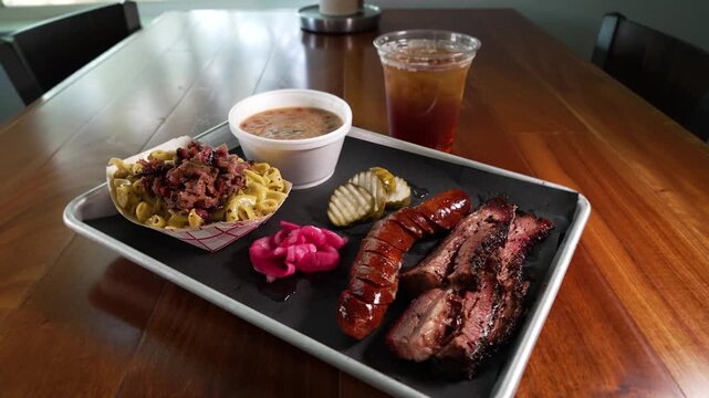 Mouthwatering Texas two meat barbecue plate, smoked sausage and tender brisket pair with chopped brisket topped macaroni and cheese and pinto beans, slider, slow motion, 4K
