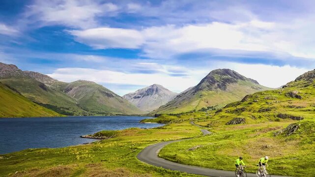 Moving clouds drift over rugged green fells and a tranquil body of water.