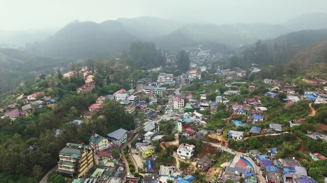 Establishing drone shot tilting over a Munnar hill station town, foggy morning