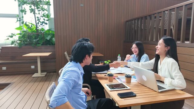 Diverse Asian Business Team Celebrating Success with High Fives on Office Terrace