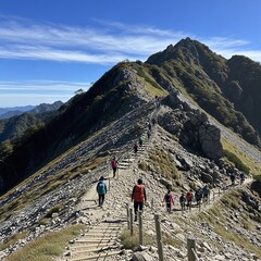 Fototapeta premium Hikers on a Mountain Ridge Under a Blue Sky.