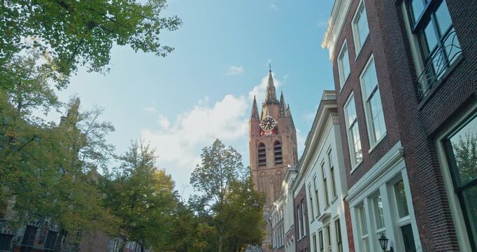 Netherlands, Europe street road view with historic brick buildings, clock tower, green trees under clear blue sky clouds