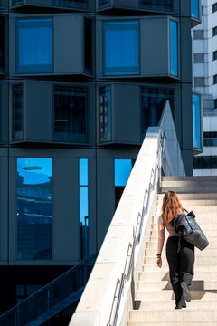 Pedestrian climbing a wide staircase between modern buildings, showing walking access, circulation and movement through contemporary city architecture