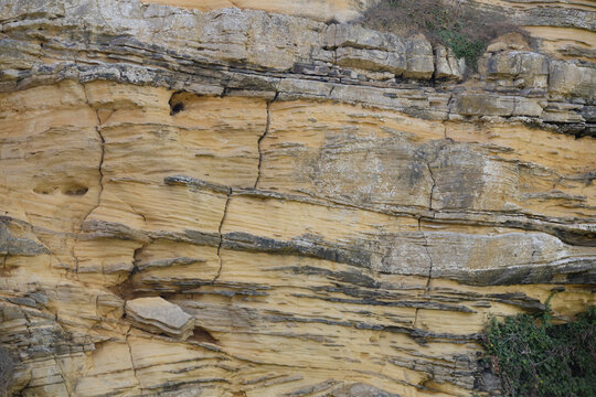 Longues-sur-Mer, France - 08 10 2026: Detail of the cliffs along the pebble beach with abstract shapes and sediments in sunny sky