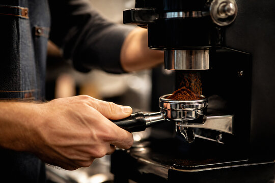 A person is tamping coffee grounds into a portafilter of an espresso machine.