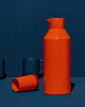 Golden orange vacuum flask with a smooth enamel finish on a teal blue background, for a long weekend and three day weekend copy space