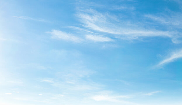 Soft clouds drift across  vast, serene blue sky