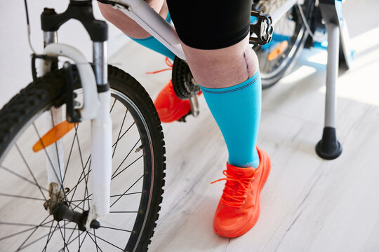 Person with leg and knee injury exercising on the bicycle at home