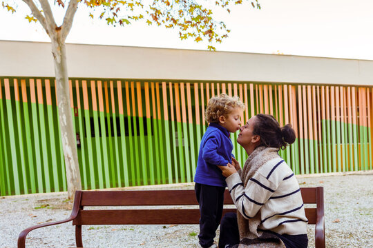 Mother and son bonding, sharing a loving kiss on the nose, expressing affection in an outdoor park setting