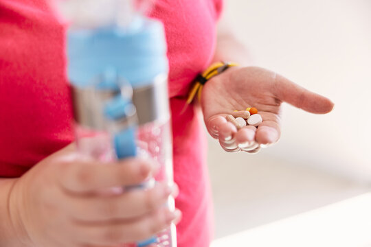 Person with water bottle and vitamins in hands