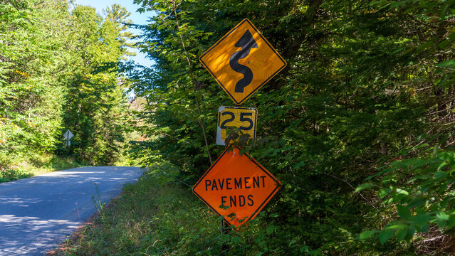 Winding road and pavement ends warning signs in the Adirondacks