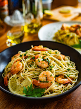 Spaghetti with fried shrimps, olive oil and parsley on wooden table