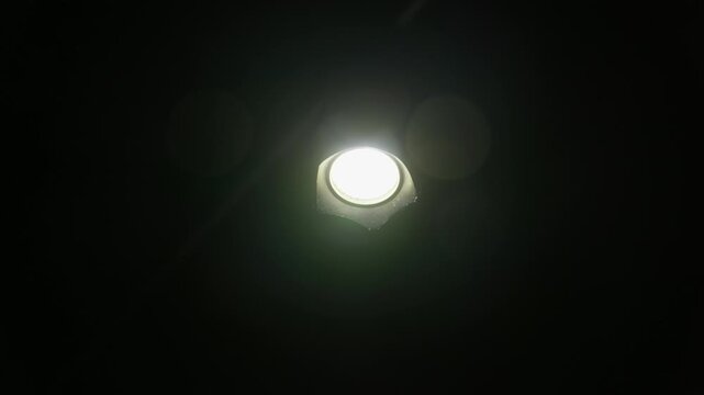 Handheld flashlight beam cuts through absolute pitch black darkness centered in front view. Sharp glowing luminance serves mystery concepts and nocturnal navigation sequences.